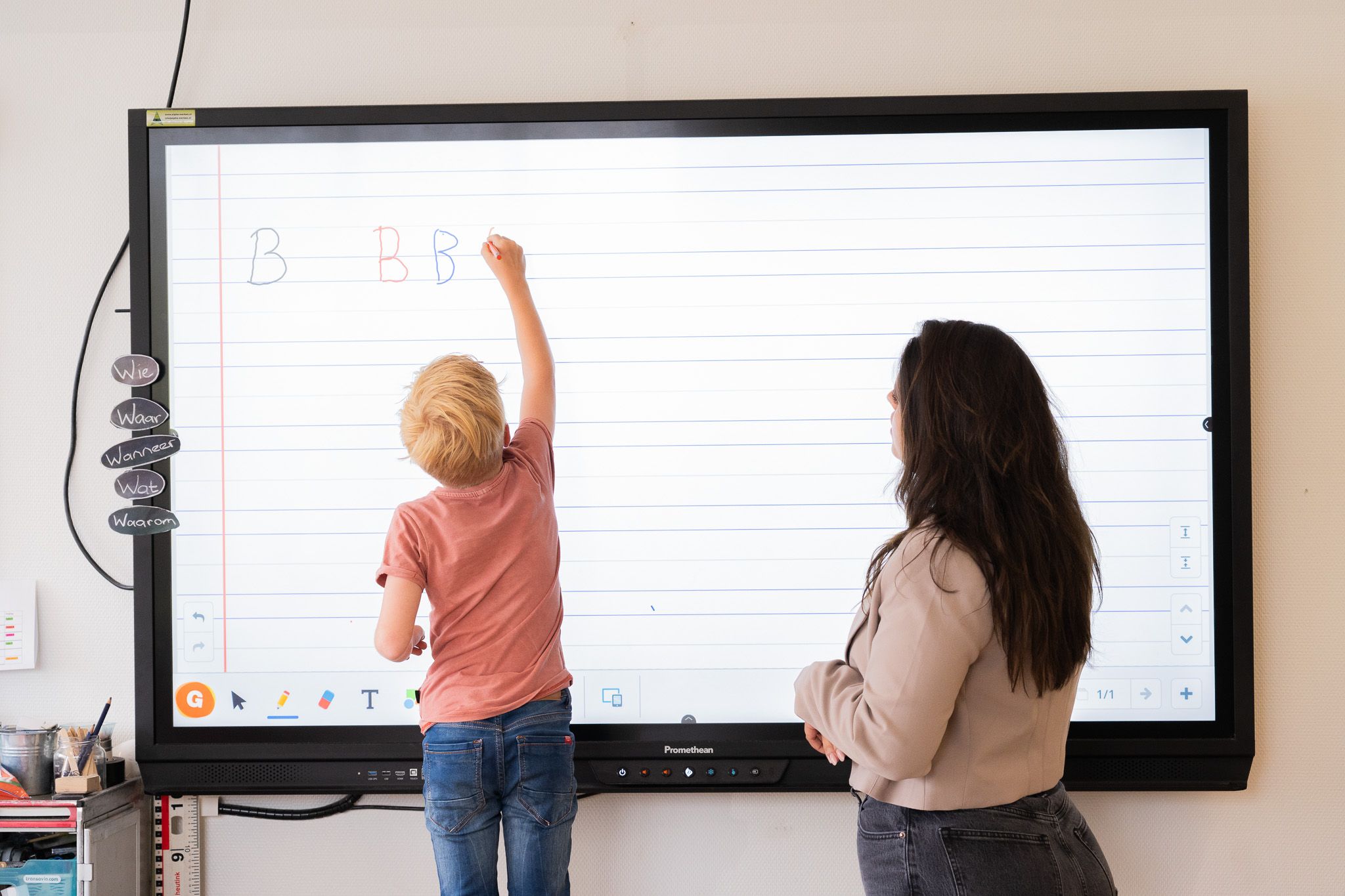 elementary student practicing letters on an interactive whiteboard